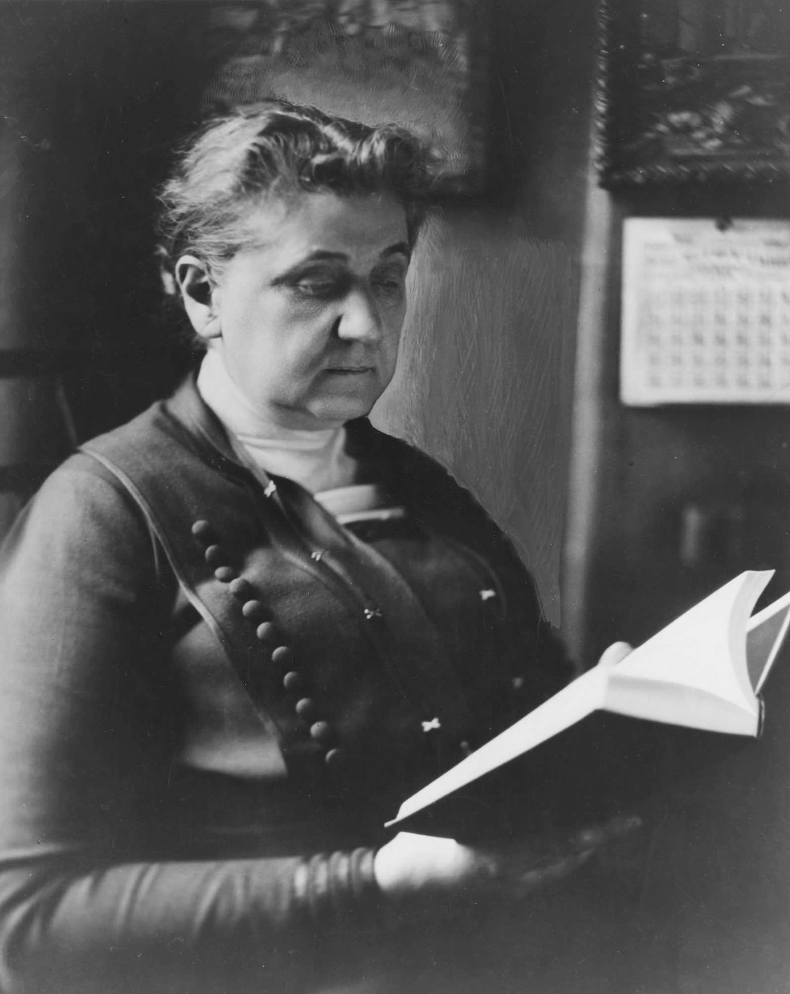 Portrait of Jane Addams, seated, reading a book, 1915.