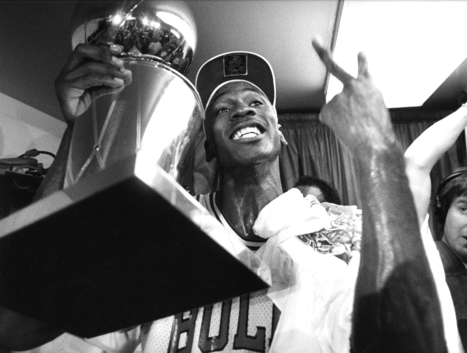 Black and white close up of Michael Jordan holding the championship trophy. The photographer angled the camera up so you can see the bottom of the trophy.