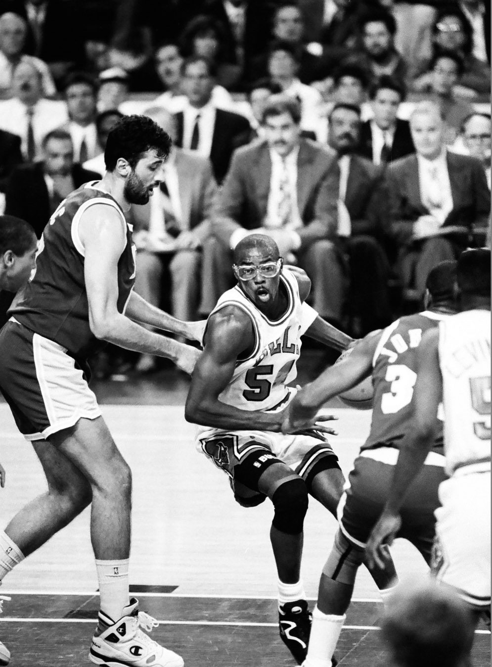 Black and white game photo. In the key, Horace Grant has control of the ball as he leans into defender Vlade Divac, who is much taller than Grant.