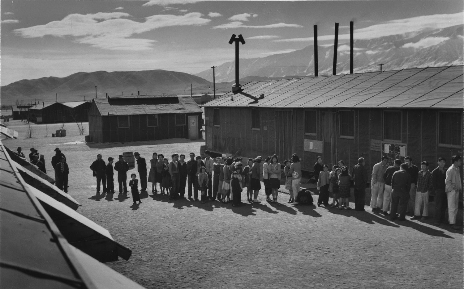 People stand in line in front of a building at meal time