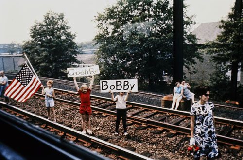 A group of young children hold up an American flag and signs reading Goodbye Bobby next to the train tracks as the Robert F. Kennedy funeral train travels from New York to Washington, District of Columbia, June 8, 1968. 