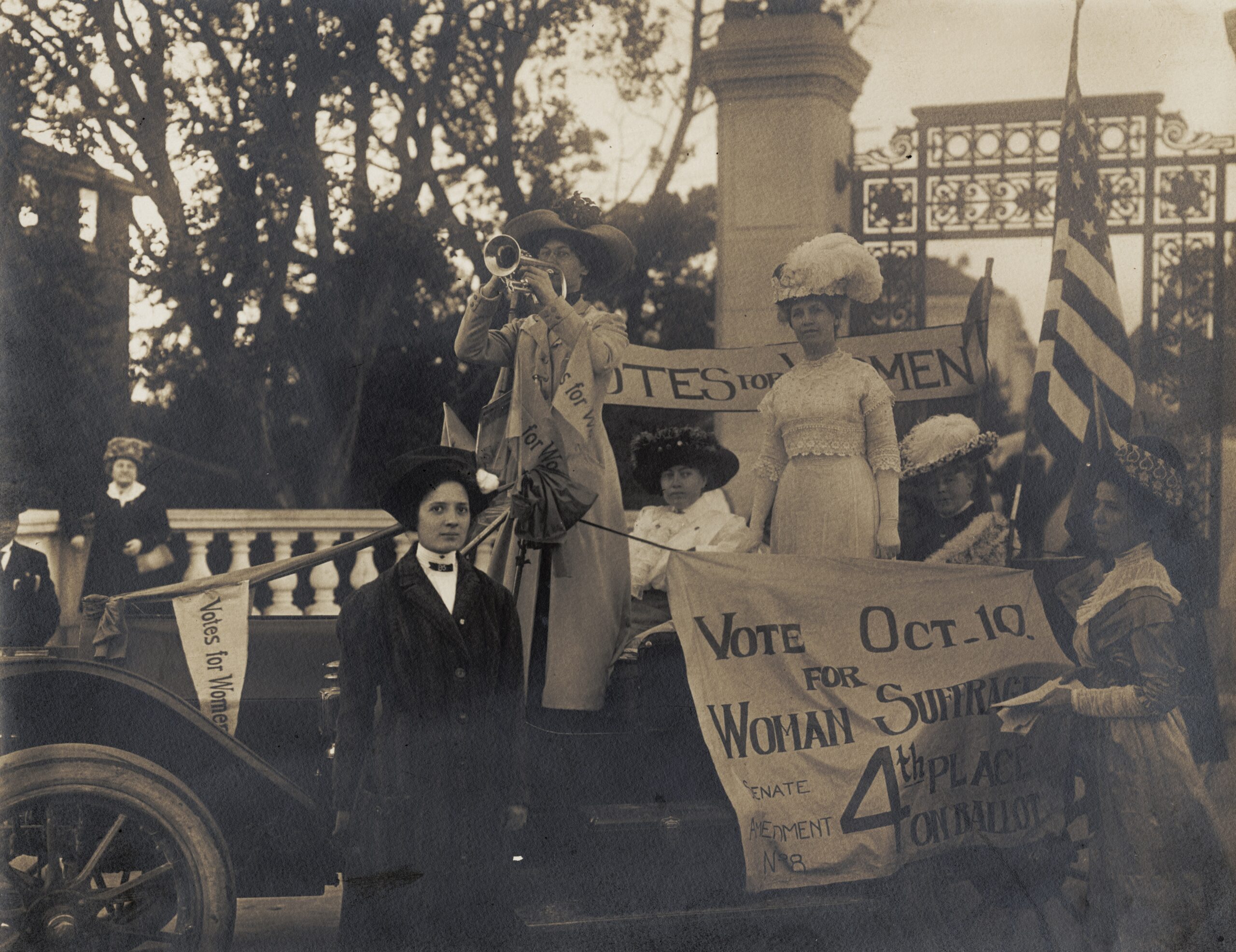 Margaret Haley in plumed hat standing in car in a women's suffrage parade
