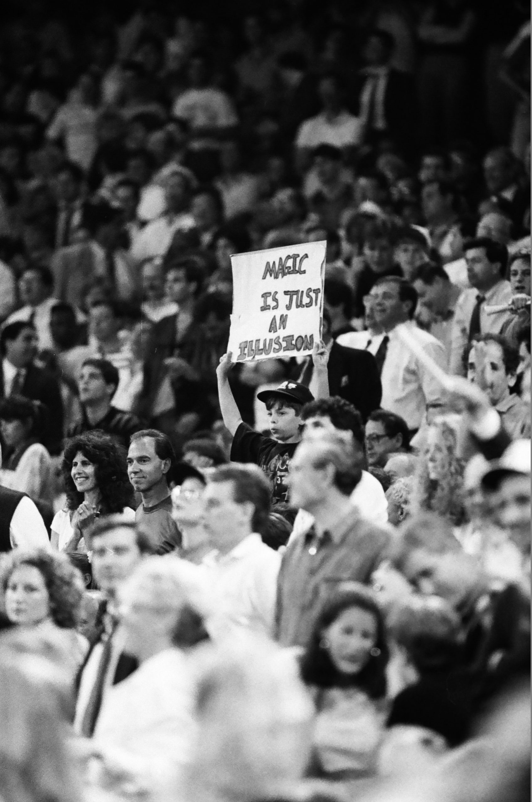 A young Bulls fan in the crowd holds a sign that reads “Magic is just an illusion"