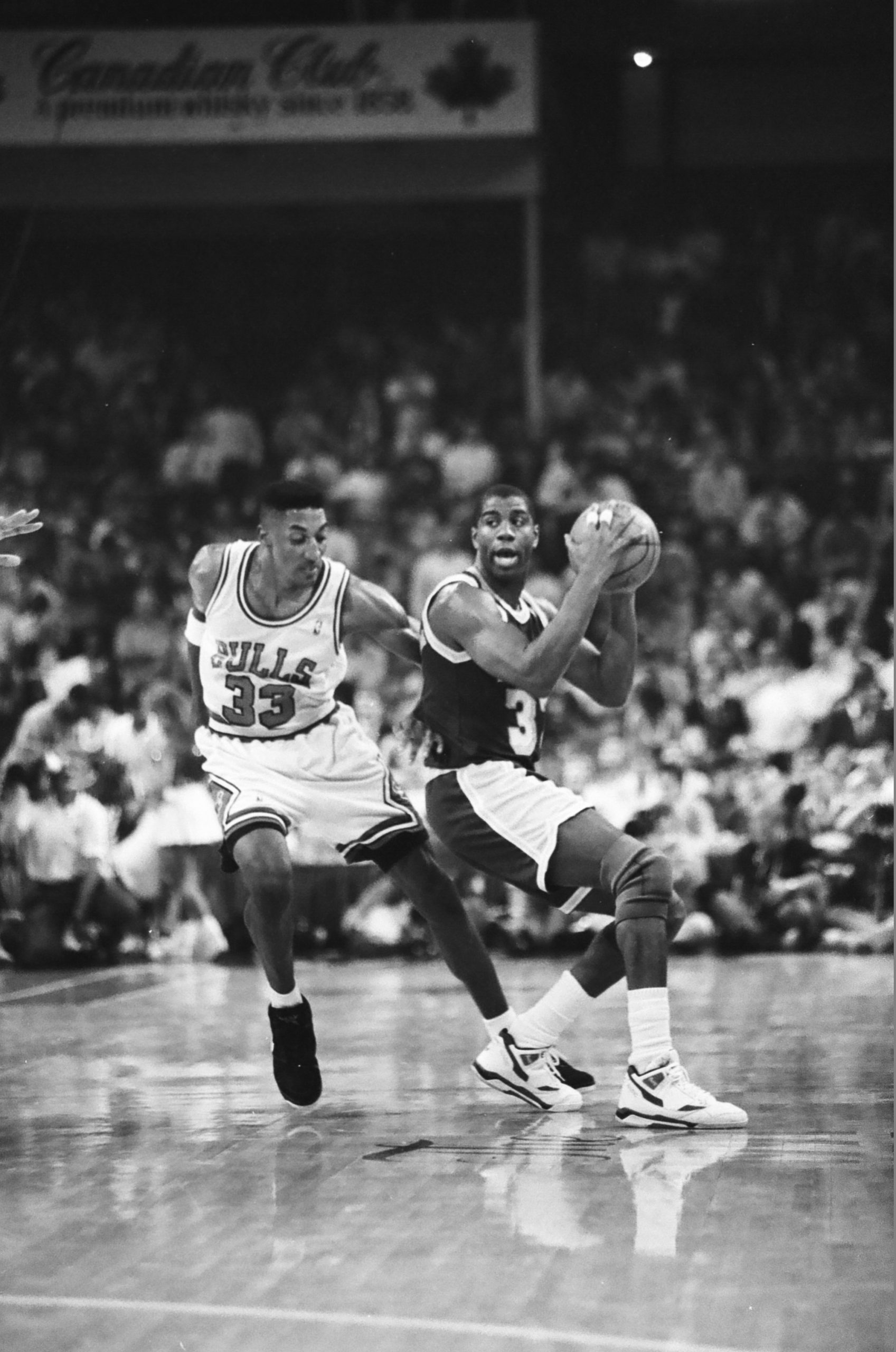 Magic Johnson holds the basketball while Scottie Pippen defends