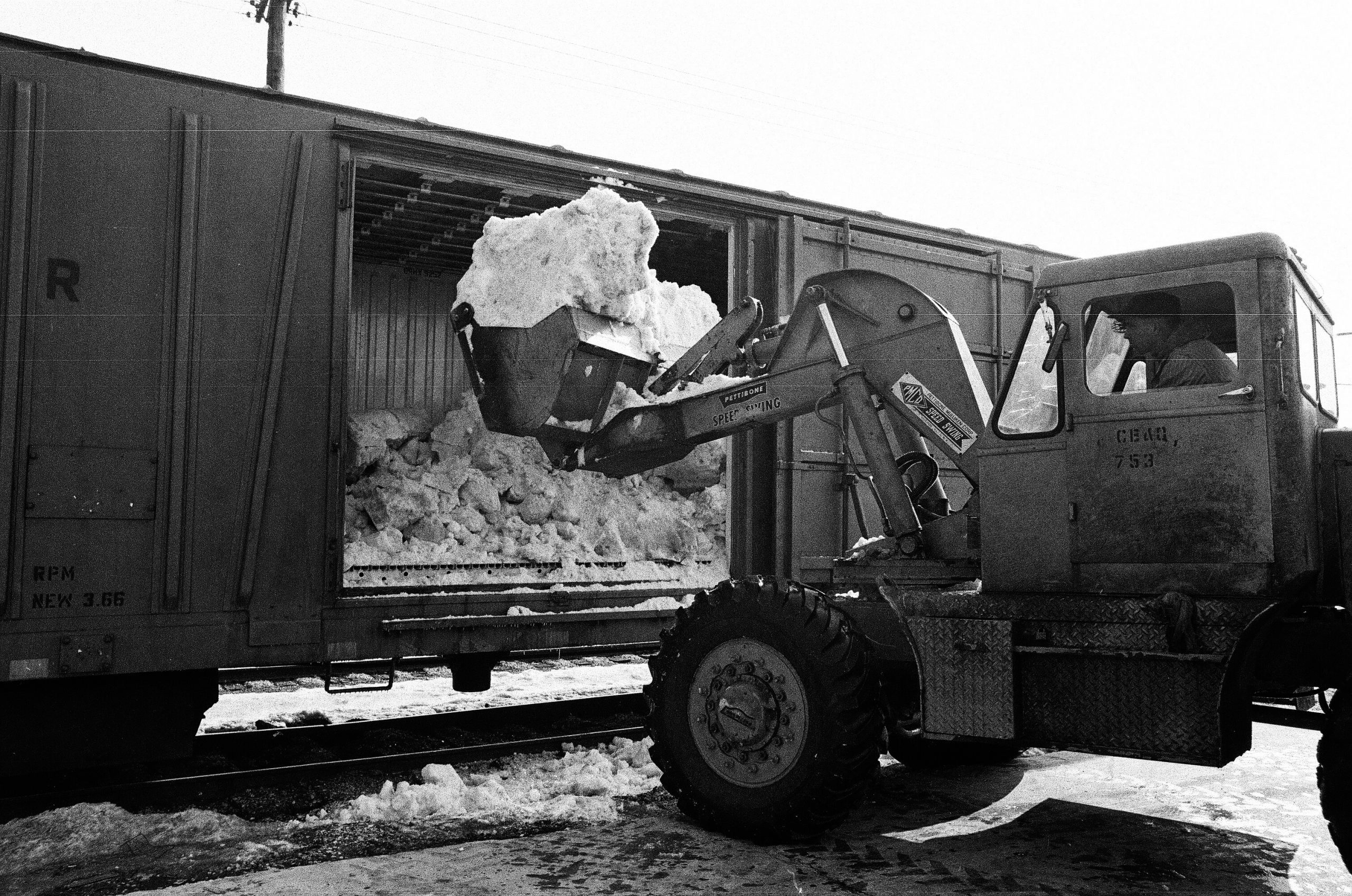 Snow being loaded into a refrigerated rail car by a bulldozer