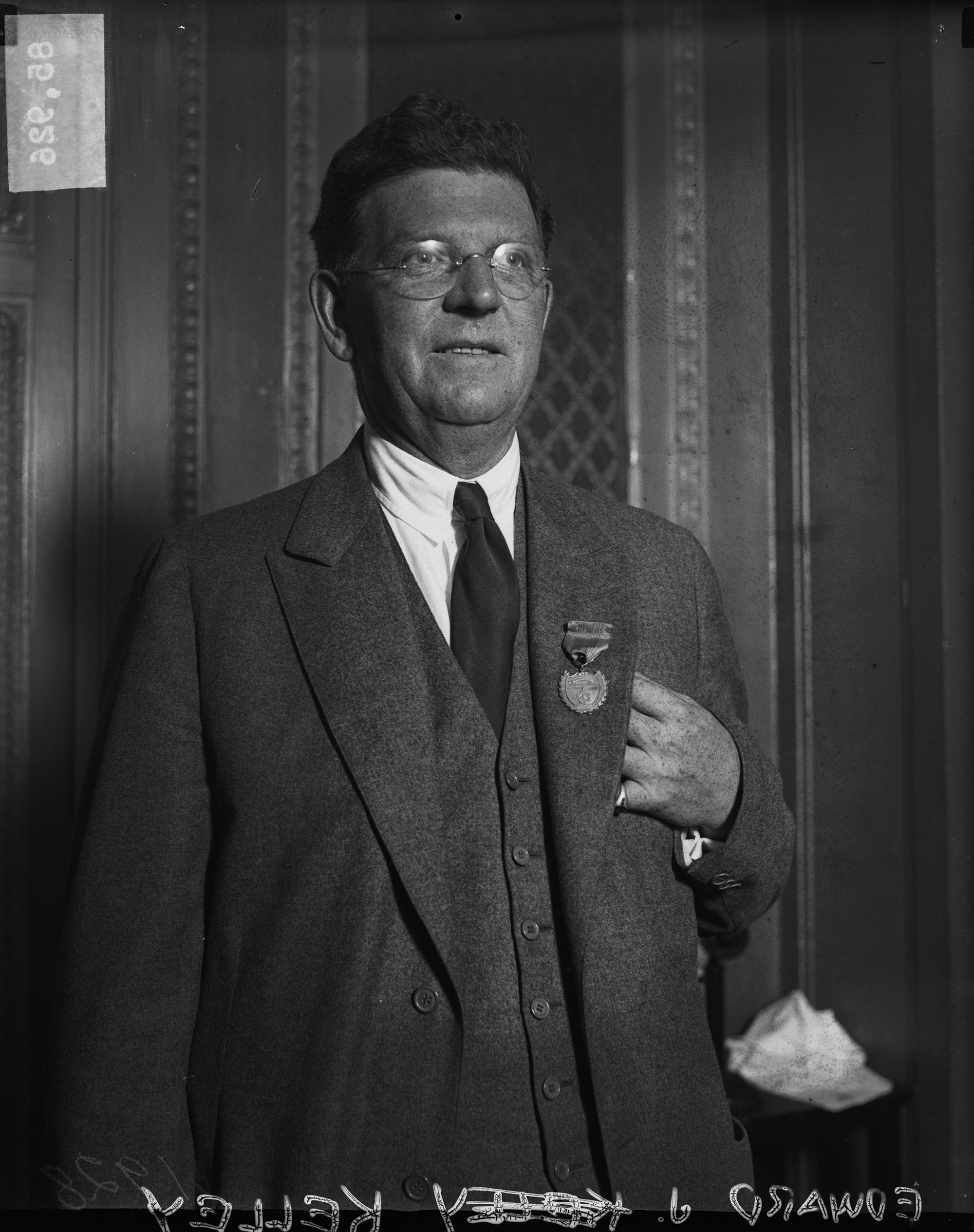 Half-length portrait of Chicago mayor Edward J. Kelly wearing a medal, standing in a room