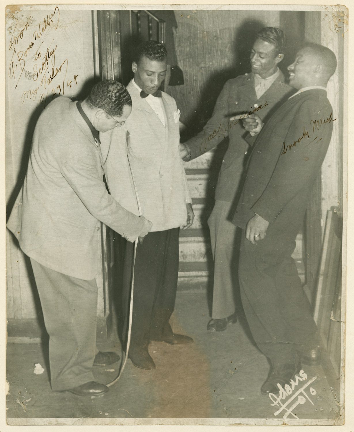 Autographed photo of T-Bone Walker being measured by tailor Scotty Piper,also pictured Jack Williams &amp; Snooky Marsh