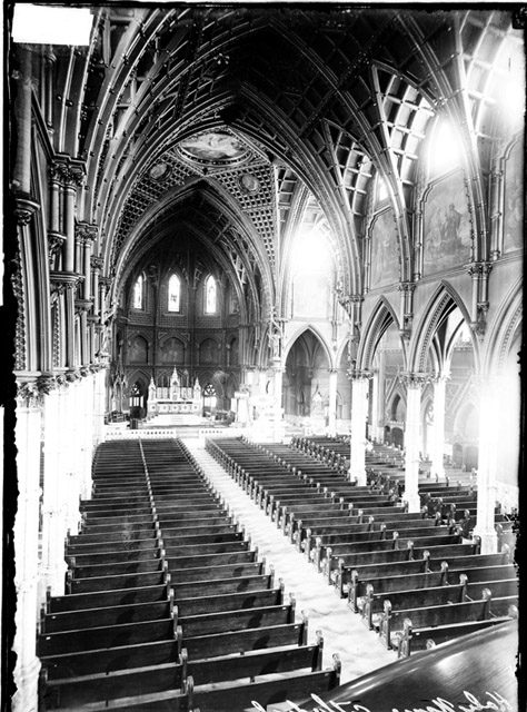 Interior view of Holy Name Cathedral at 735 North State Street in the Near North Side community area of Chicago, Illinois. This image shows the view looking from a raised vantage point behind the pews toward the altar.